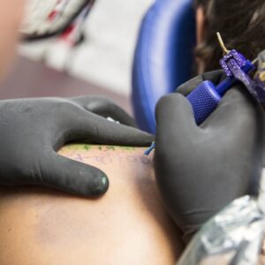 Close Up Of Tattooist Giving Customer Their First Tattoo